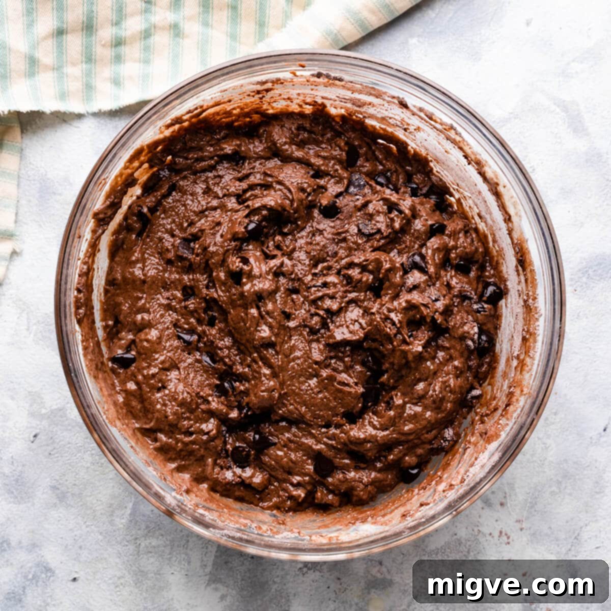 A large bowl filled with rich chocolate fudge muffin batter, showing its thick and lumpy consistency.