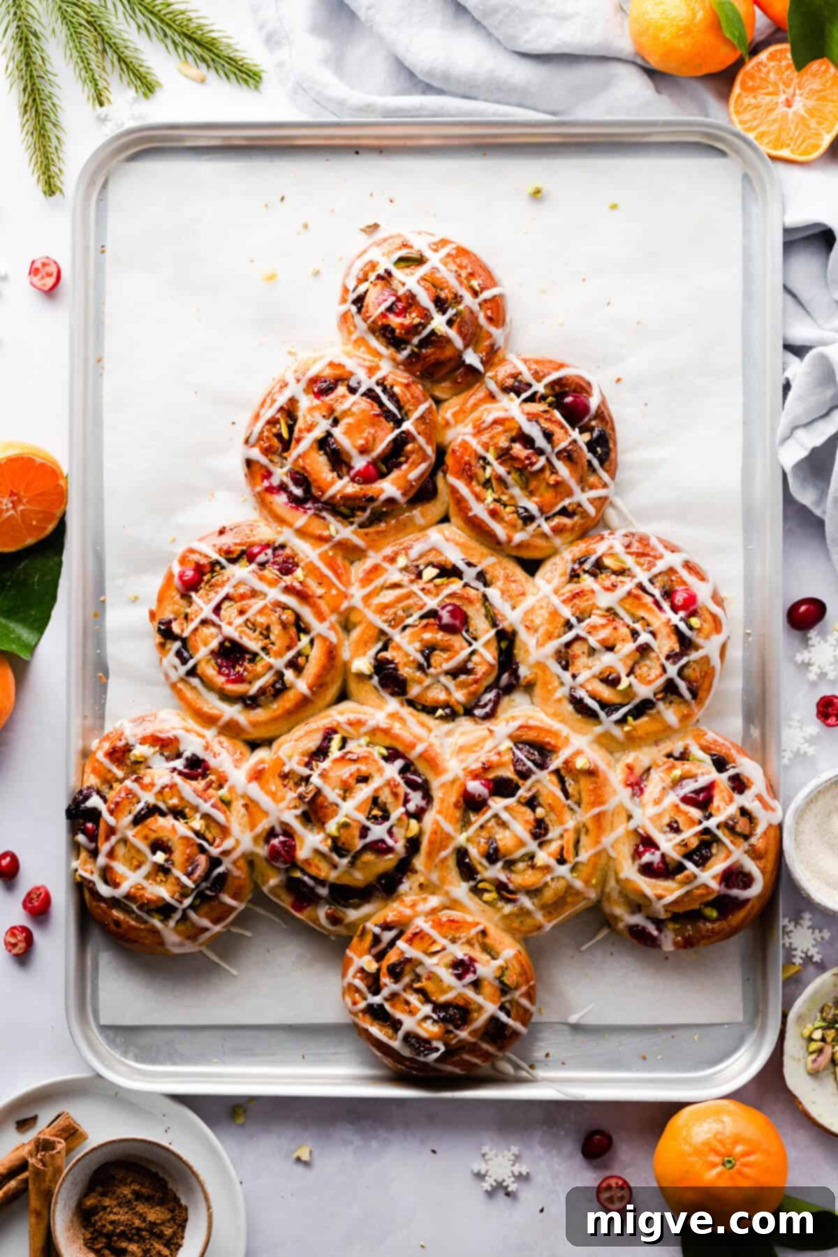 Overhead shot of Chelsea buns shaped into a Christmas tree and drizzled with a sweet sugar glaze, showcasing their festive appeal for holiday breakfasts and brunches.