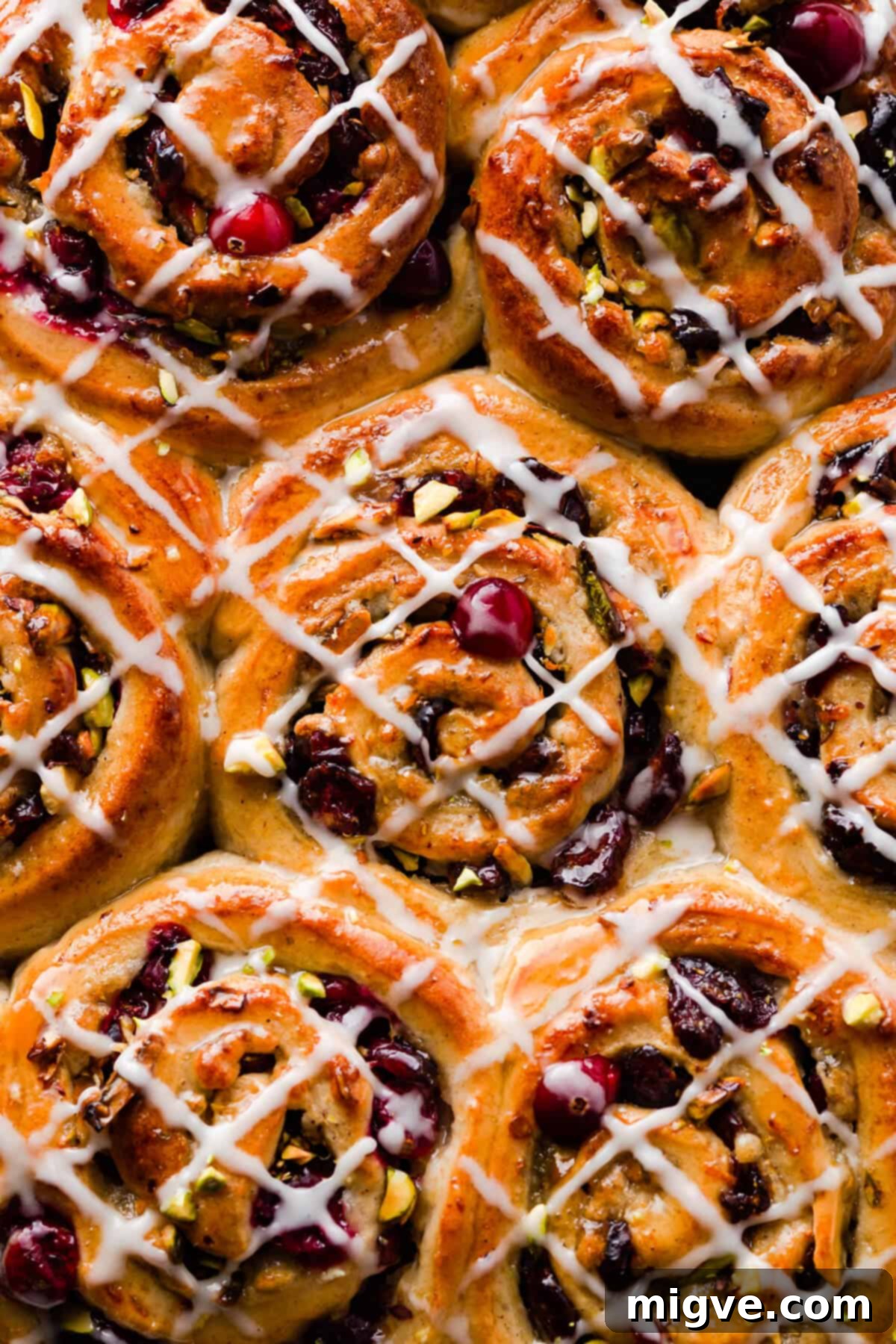 Super close-up top view of cranberry-filled Chelsea buns with a glistening sugar glaze, showcasing their moist interior and festive appeal.