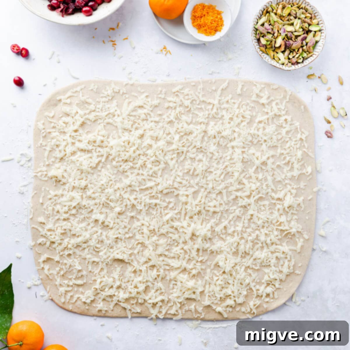 Rolled out dough for Chelsea buns, evenly topped with grated marzipan, preparing for the next layer of festive filling.