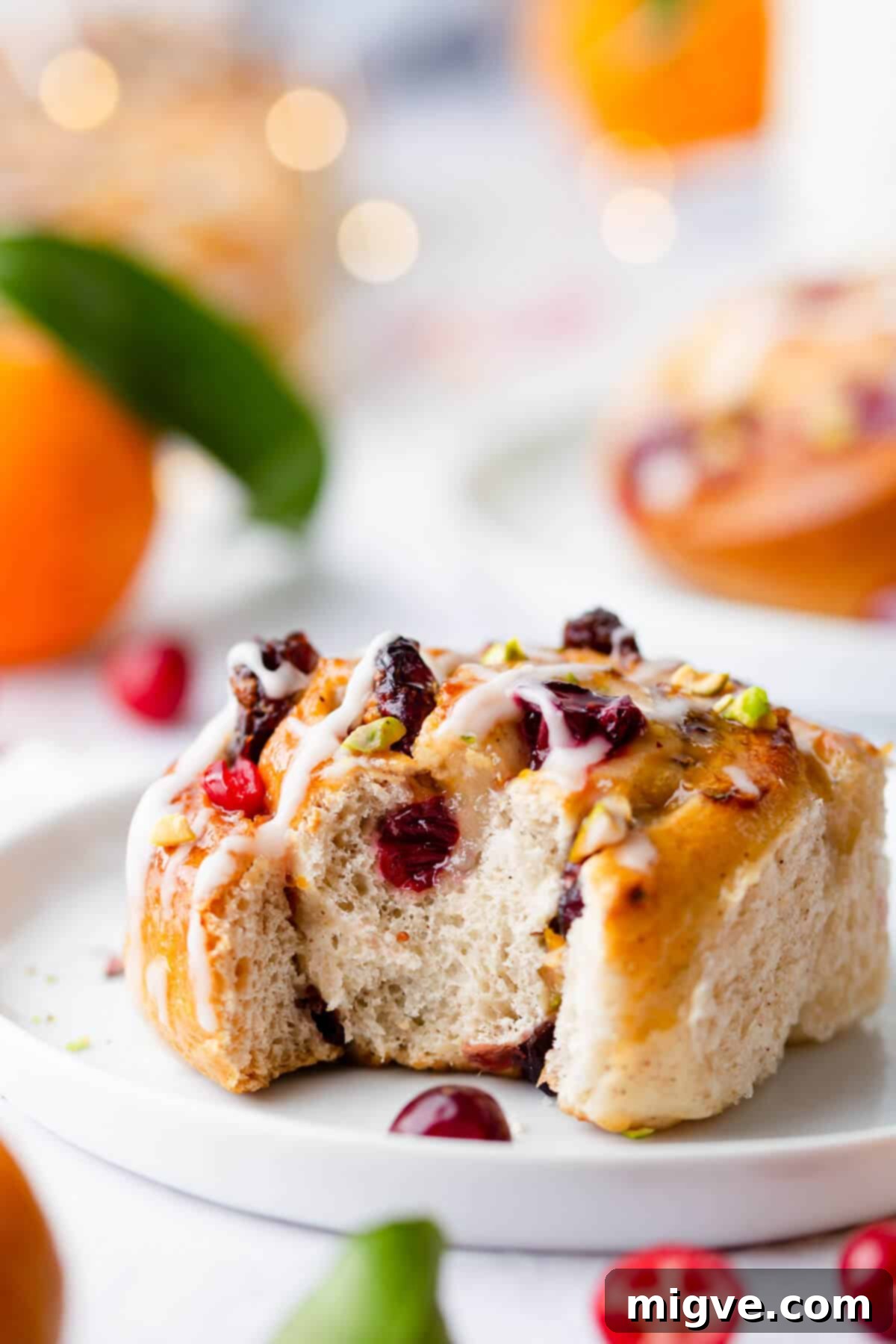 Super close-up side view of a moist and fluffy Chelsea bun with a bite taken out, revealing the rich cranberry and marzipan filling.