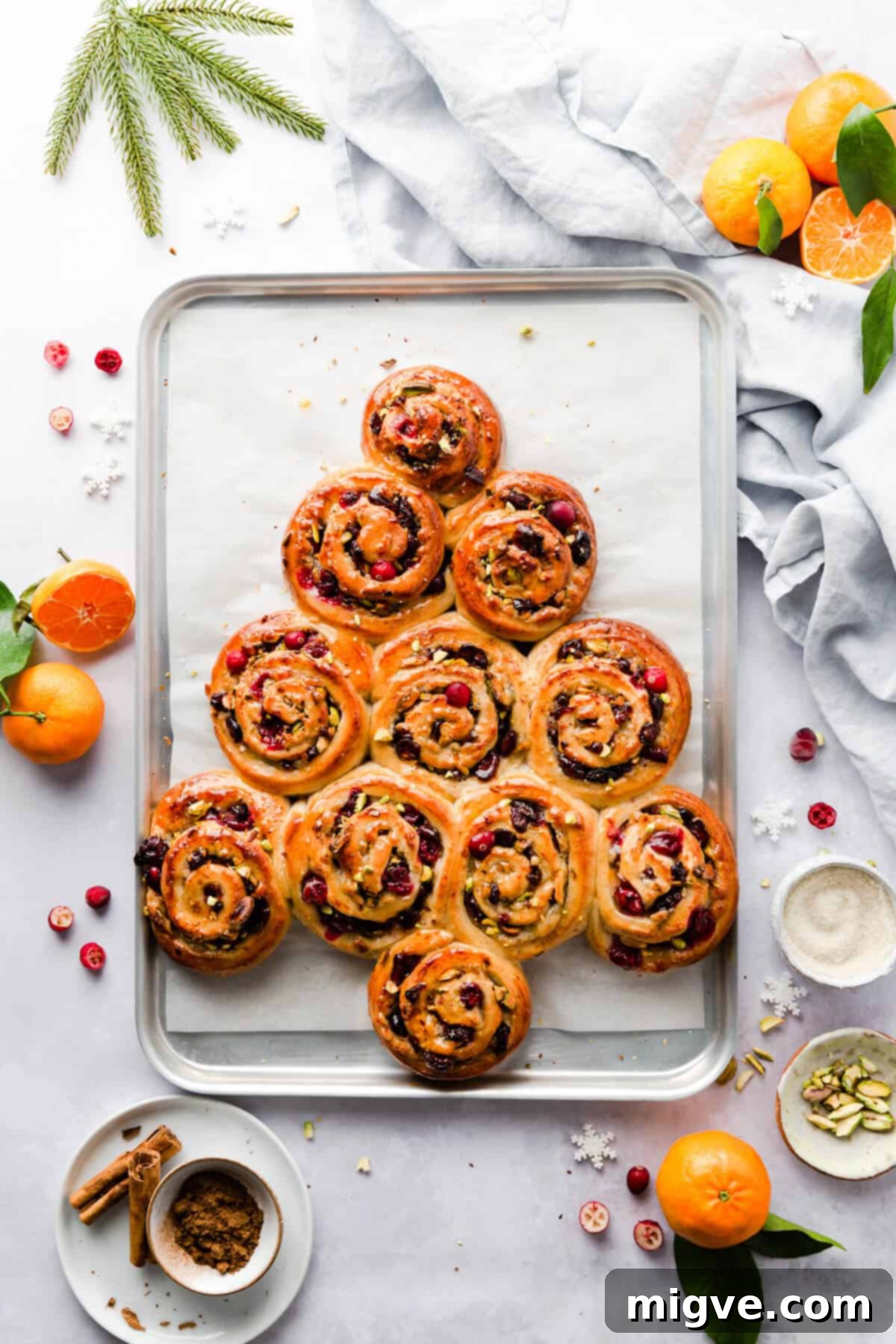 Top view of orange and cranberry Chelsea buns, freshly baked and arranged into a festive Christmas tree shape on a baking tray.