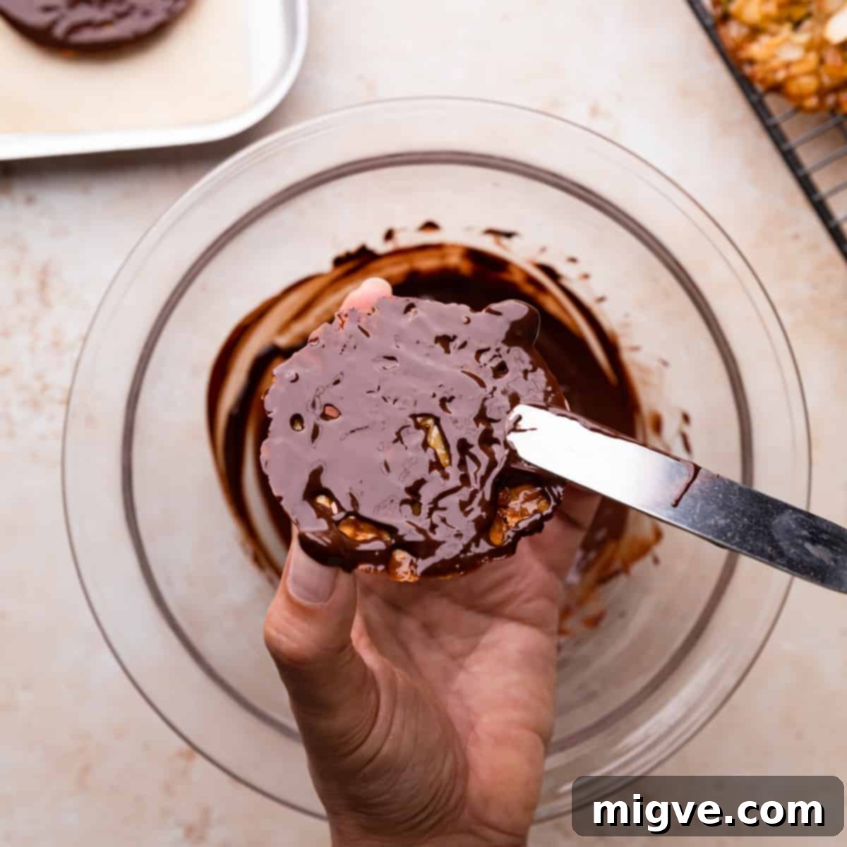 Florentine Almond Lace 11 The back of a florentine cookie being covered with melted dark chocolate using a palette knife, creating an even layer.