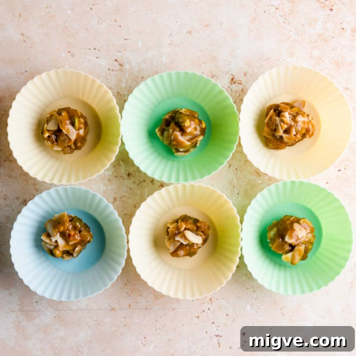 Florentine Almond Lace 13 Six individual silicone cupcake cases, each containing a small portion of almond florentine cookie batter, ready for baking.