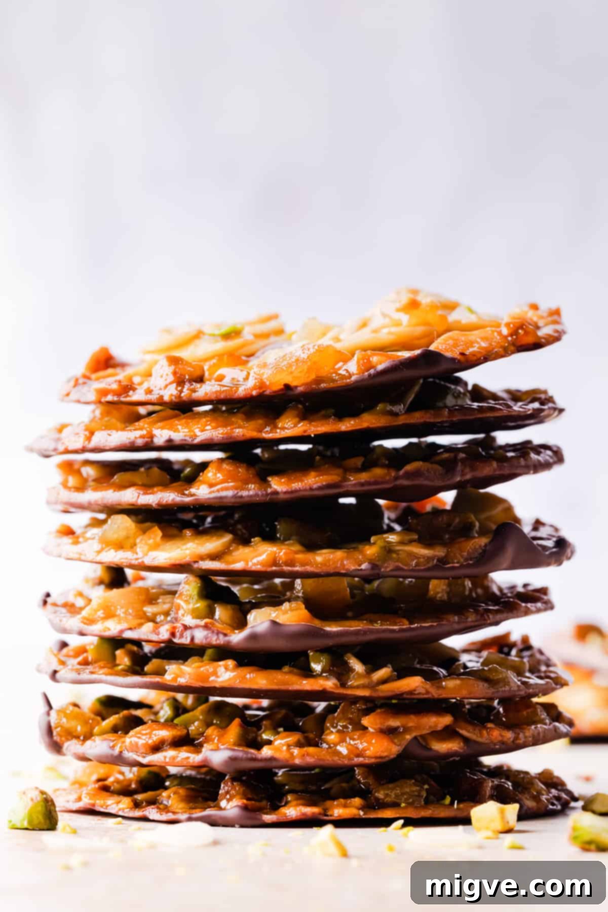 Florentine Almond Lace 19 Tall stack of thin, perfectly golden florentine cookies with visible flaked almonds and pistachios, ready to be enjoyed.