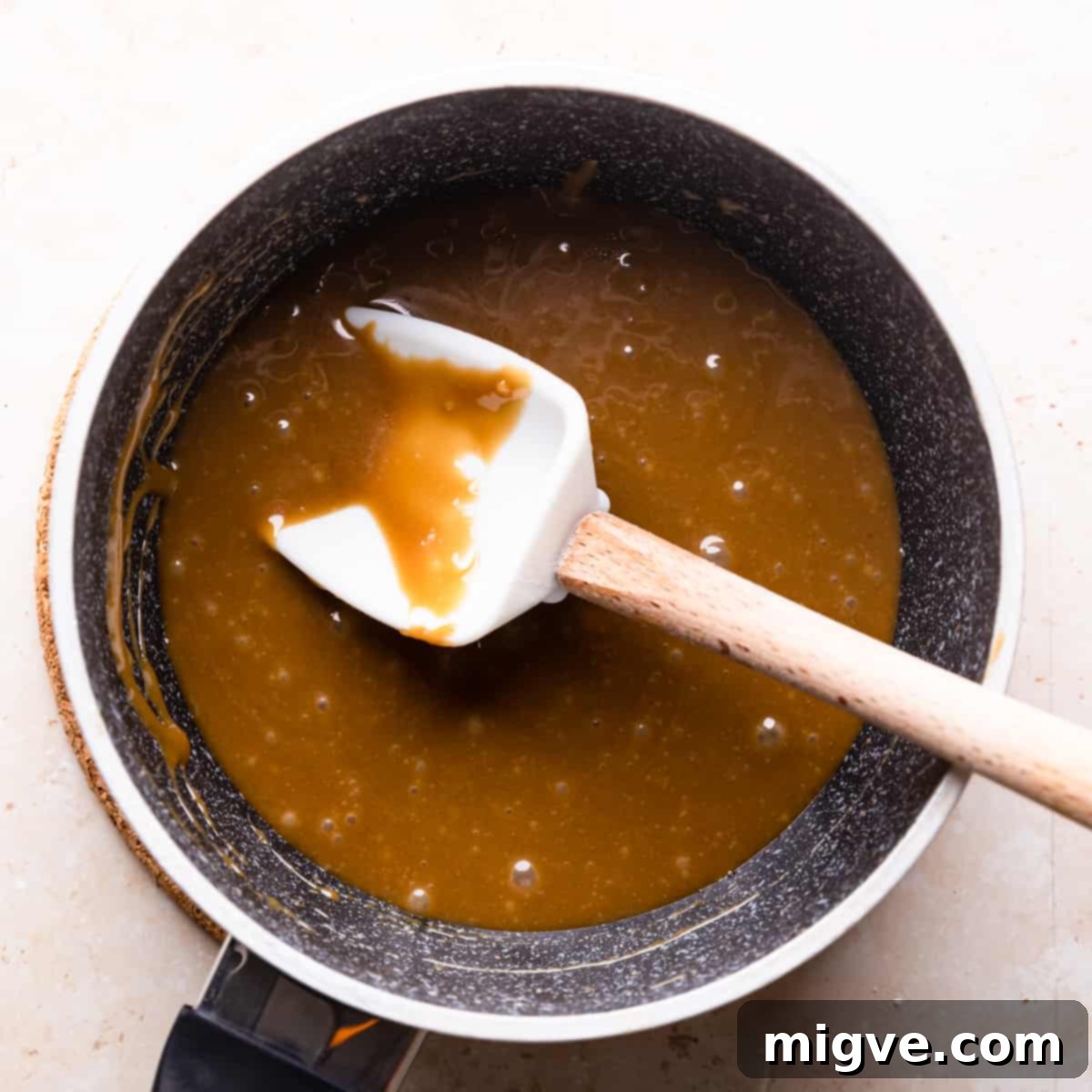 Florentine Almond Lace 5 Small saucepan containing the smooth, thick caramel sauce for almond florentines, with a white spatula resting in the pan.