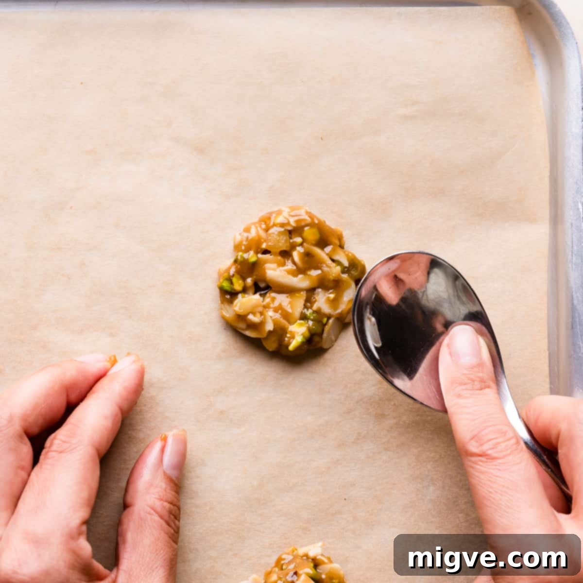 Florentine Almond Lace 8 Mixture for almond florentine cookies being gently pressed into flat, uniform disks with the back of a spoon on a baking sheet.