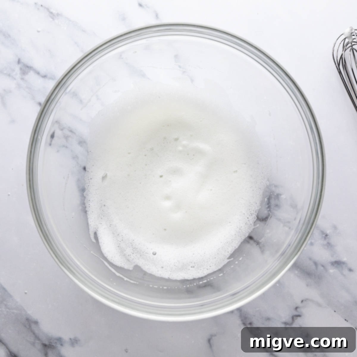 large mixing bowl with frothy egg white.