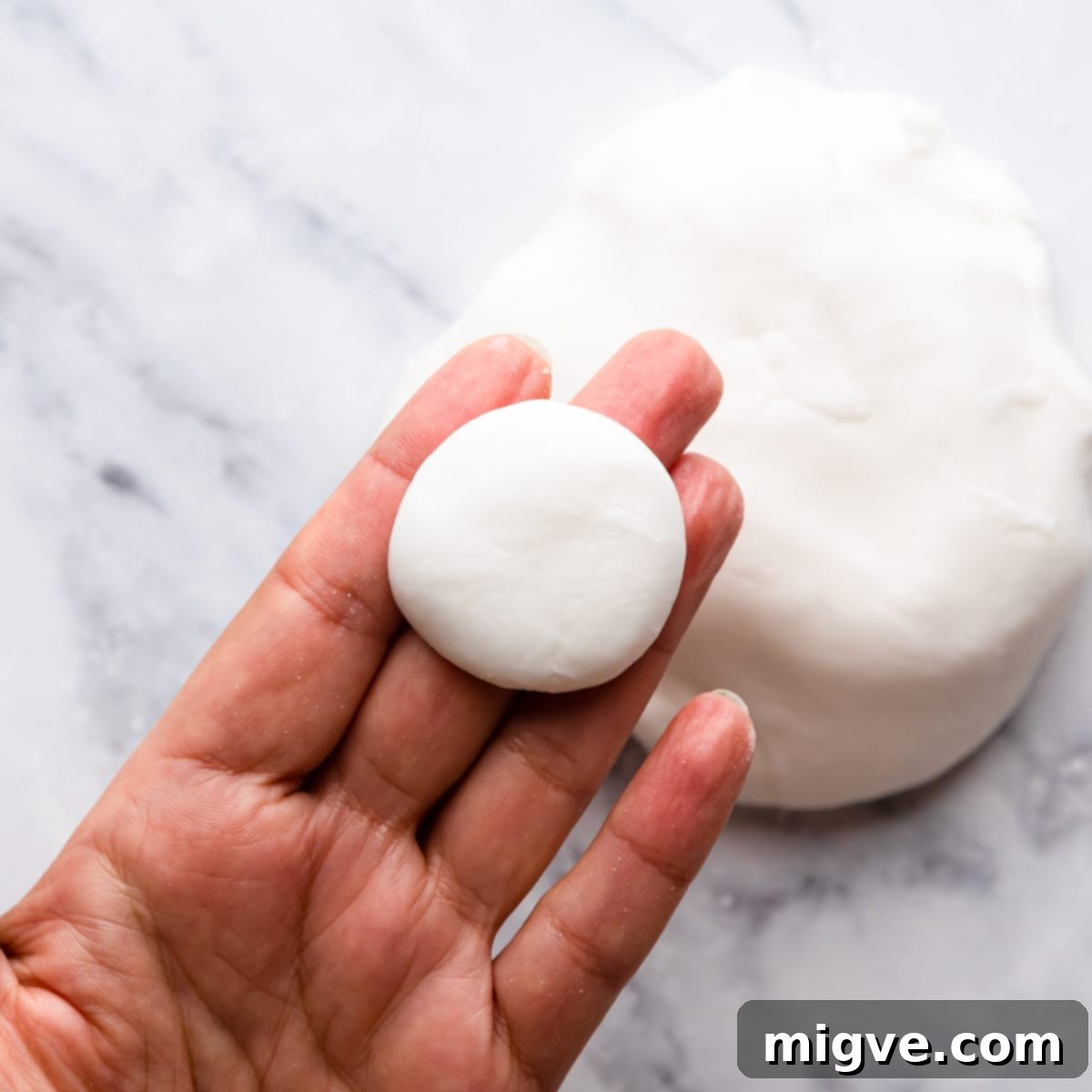small piece of dough for mint creams shaped into flat disc held on someone's hand.