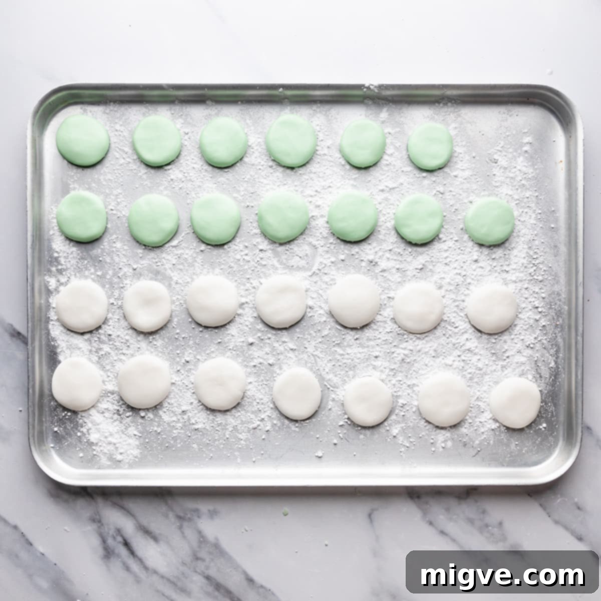 silver metal tray dusted with icing sugar and filled with white and green peppermint cream patties.