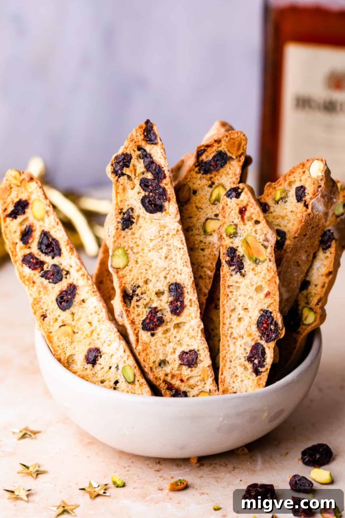 Ruby Red Biscotti 12 biscotti cookies standing up inside of ceramic bowl with some dried cranberries on side.