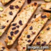 Ruby Red Biscotti 13 slices of individual biscotti with cranberries on a brown baking paper.