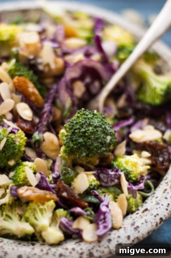 Crunchy broccoli salad with creamy cashew dressing, showcasing fresh ingredients like broccoli, red cabbage, and almonds