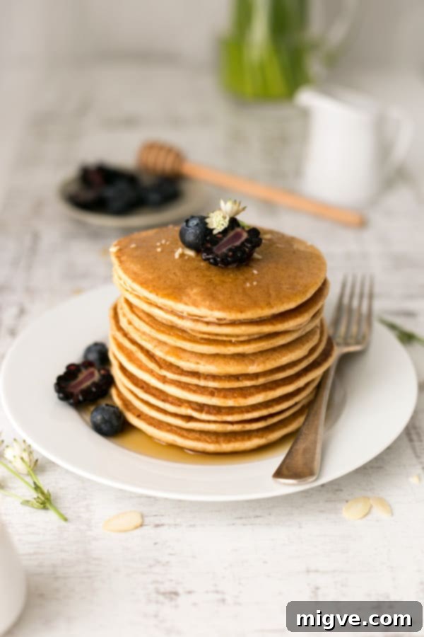 Delicious breakfast tofu pancakes drizzled with maple syrup and scattered with fresh berries on a white plate