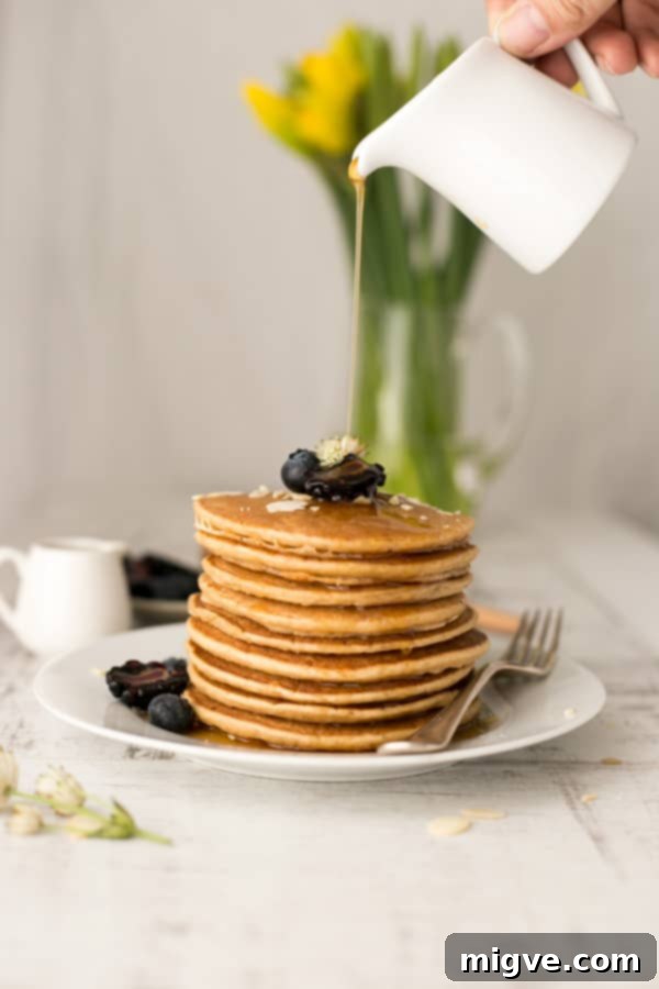 Close-up of a stack of breakfast tofu pancakes with intricate maple syrup patterns and vibrant berries