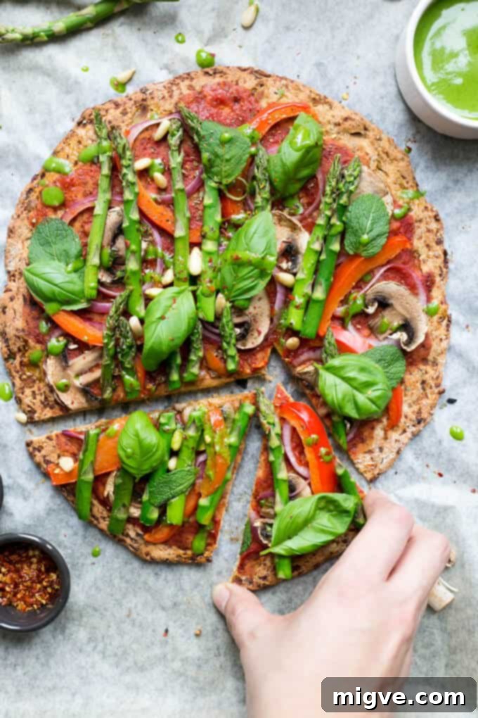 Delicious Cauliflower Pizza Crust topped with vibrant asparagus and a fresh spinach dressing, a perfect healthy meal.