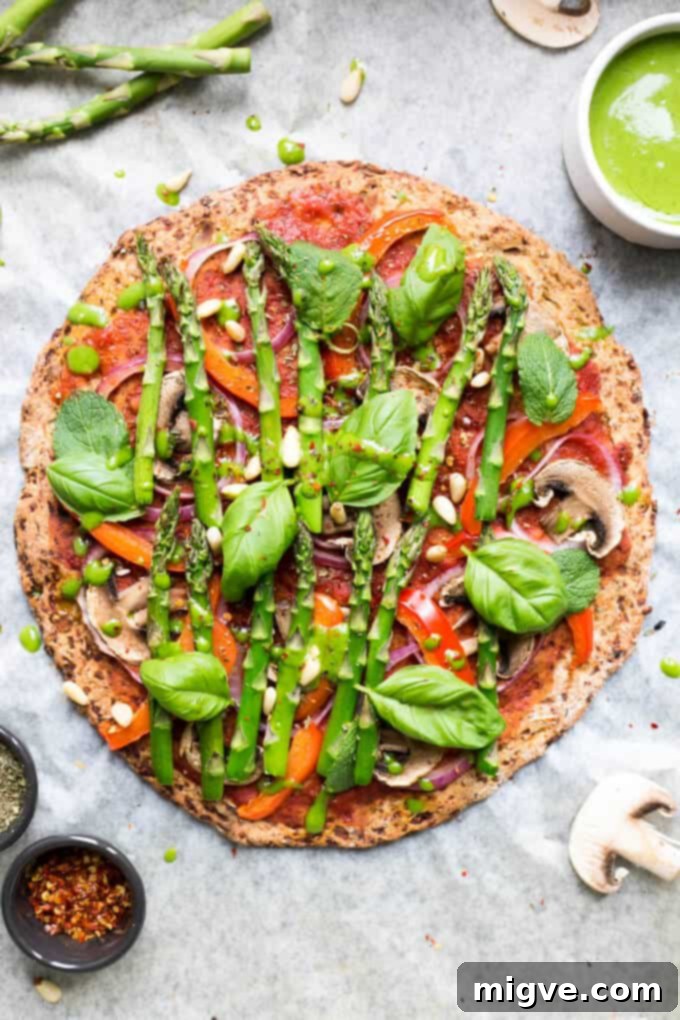 A visually appealing Cauliflower Pizza Crust garnished with tender asparagus, captured up close to highlight its fresh preparation.
