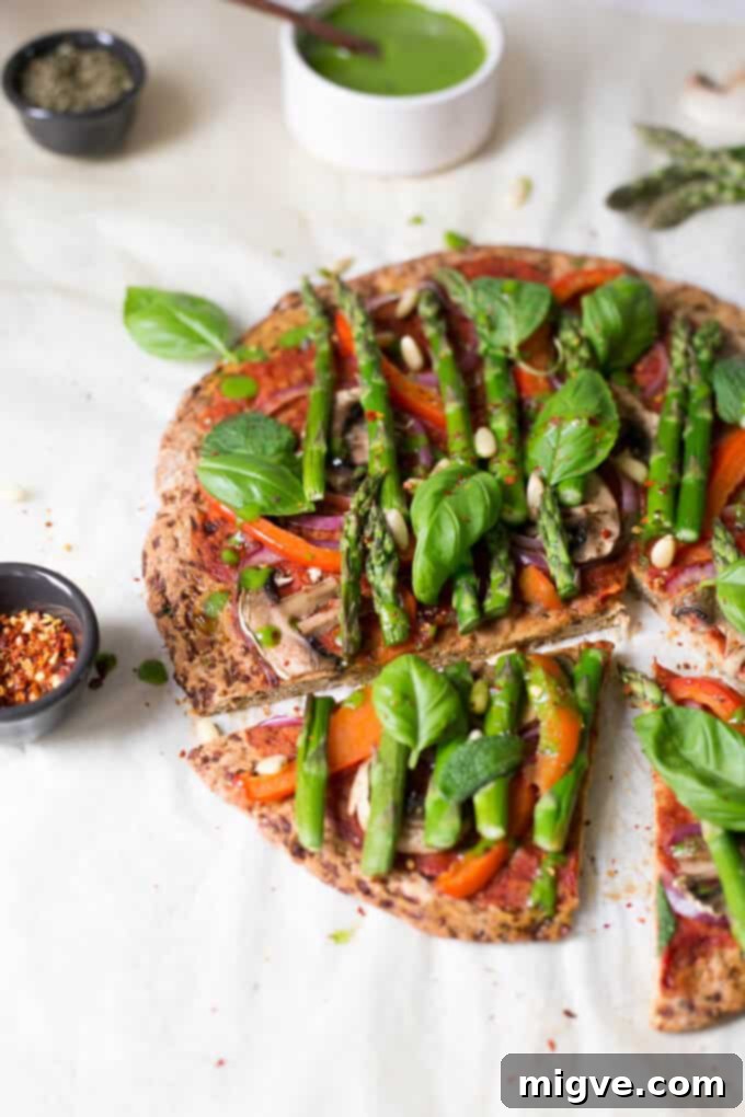 Artfully presented Cauliflower Pizza Crust, complete with tender asparagus and a swirl of spinach dressing, highlighting its healthy ingredients.