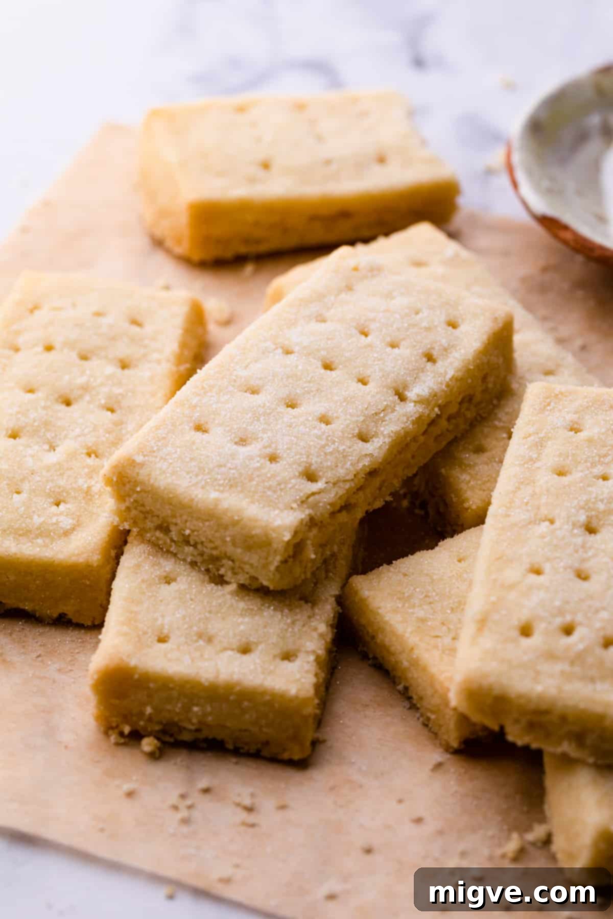 Slices of golden shortbread fingers on brown baking paper, showcasing their delicate texture.