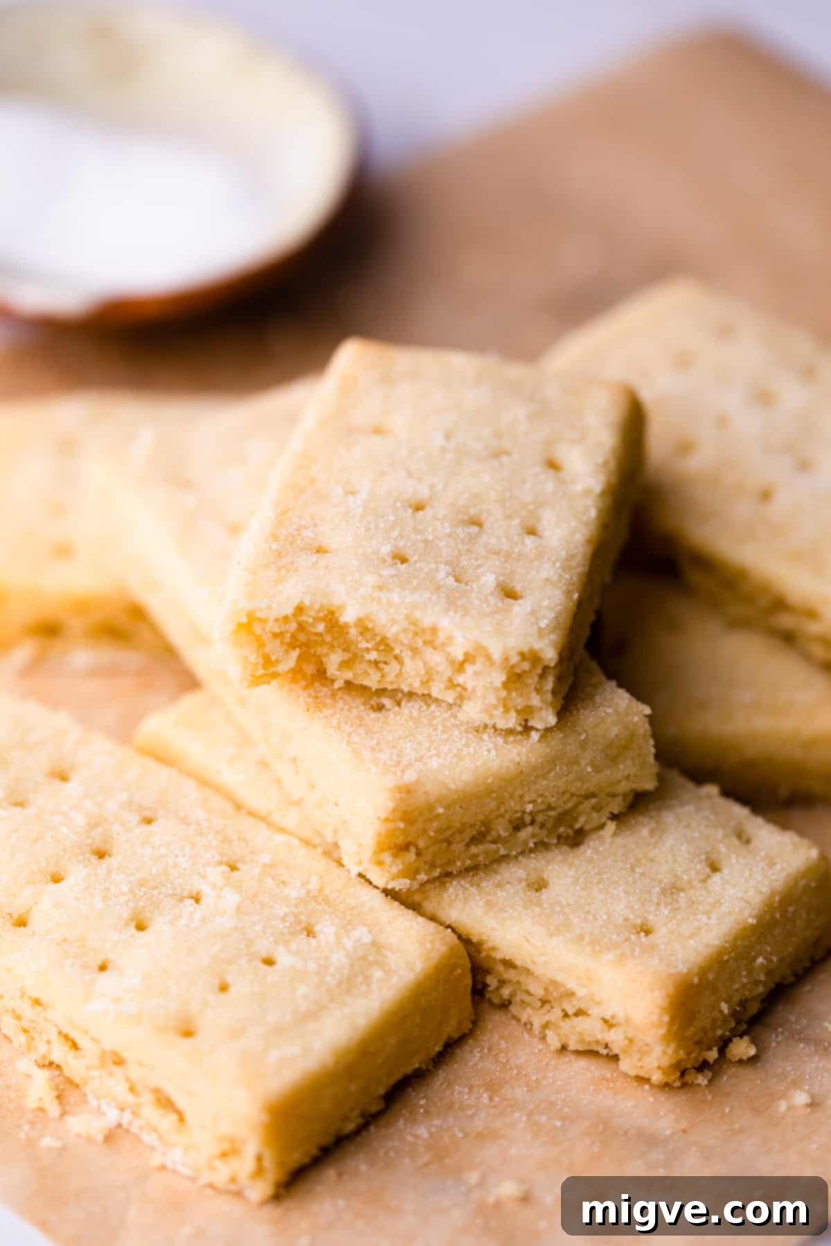An array of beautifully baked shortbread fingers, some dusted with sugar, resting on a baking sheet.