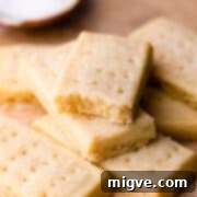 Scottish shortbread biscuits sprinkled with sugar on a brown baking paper and one biscuit missing a bite.