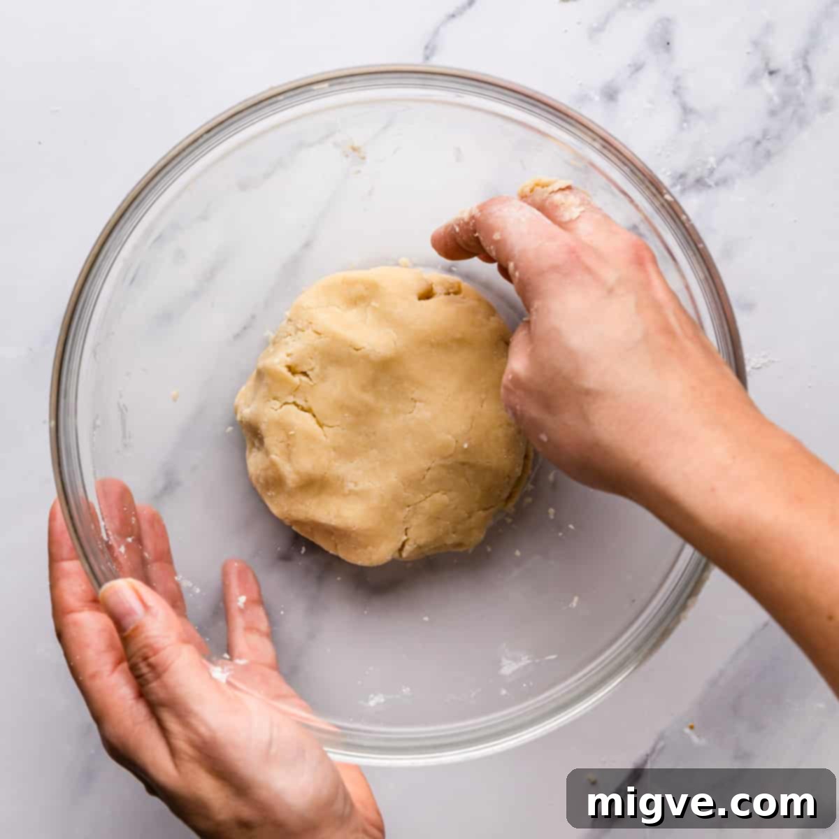 Shortbread dough forming inside a glass mixing bowl, showcasing its cohesive texture.