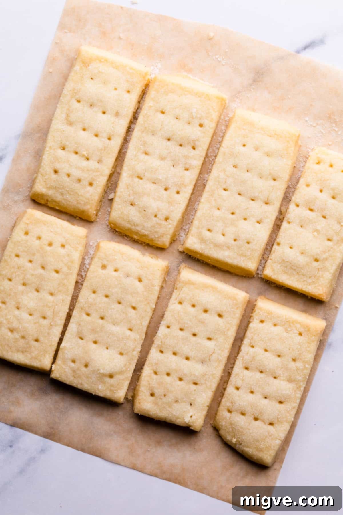 A batch of perfectly baked shortbread biscuits cooling on a baking tray lined with parchment paper.