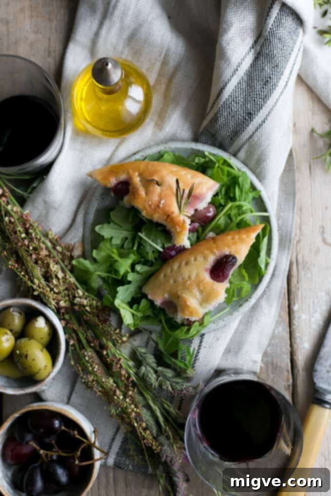 Freshly baked rosemary focaccia bread with roasted red grapes and sea salt, ready for serving
