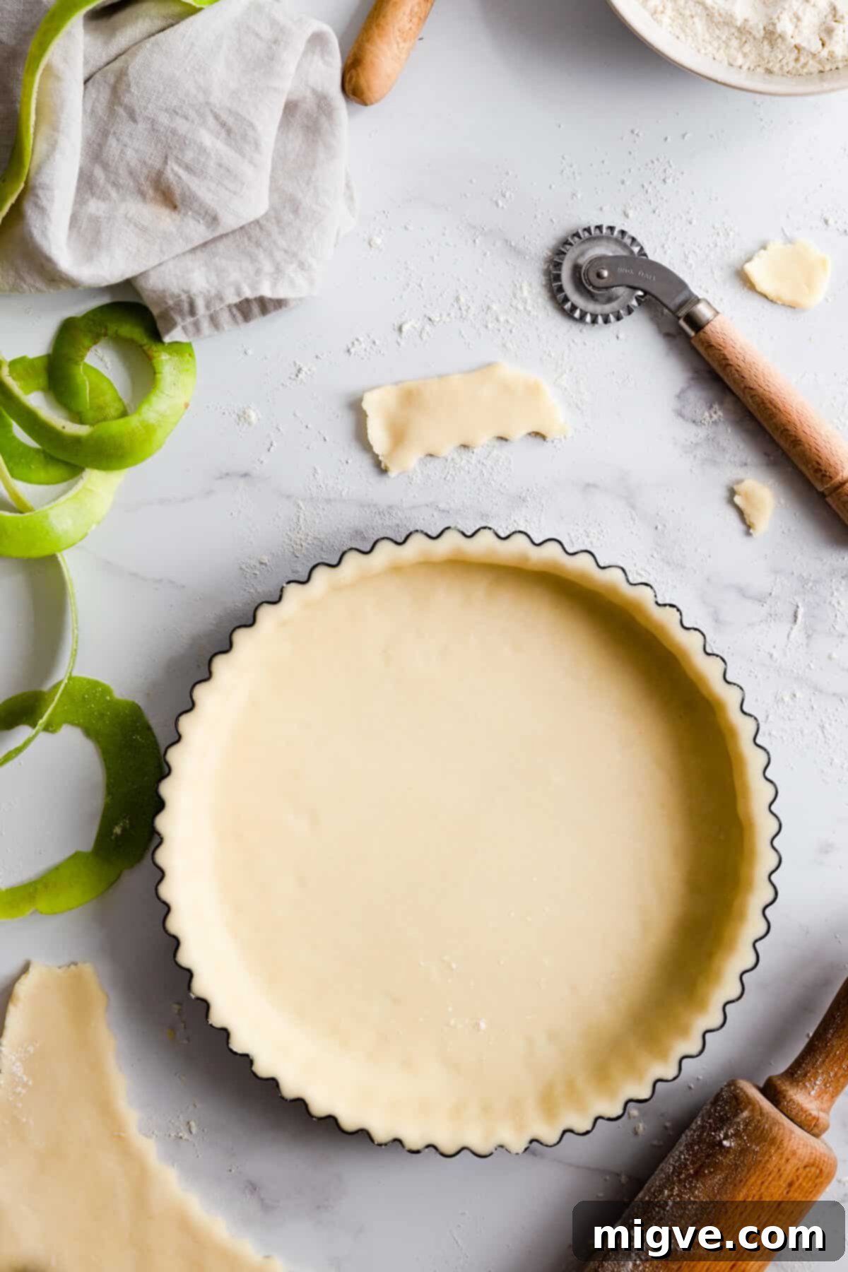 Top-down view of a baking tin lined with a perfectly pressed shortcrust pastry, forming the base for an upcoming pie.