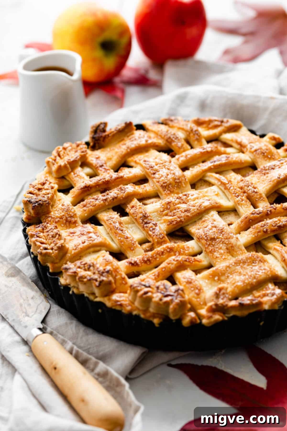 A close-up side view of a perfectly baked apple pie, highlighting its golden-brown, flaky lattice crust and the substantial apple filling beneath, suggesting delicious warmth.
