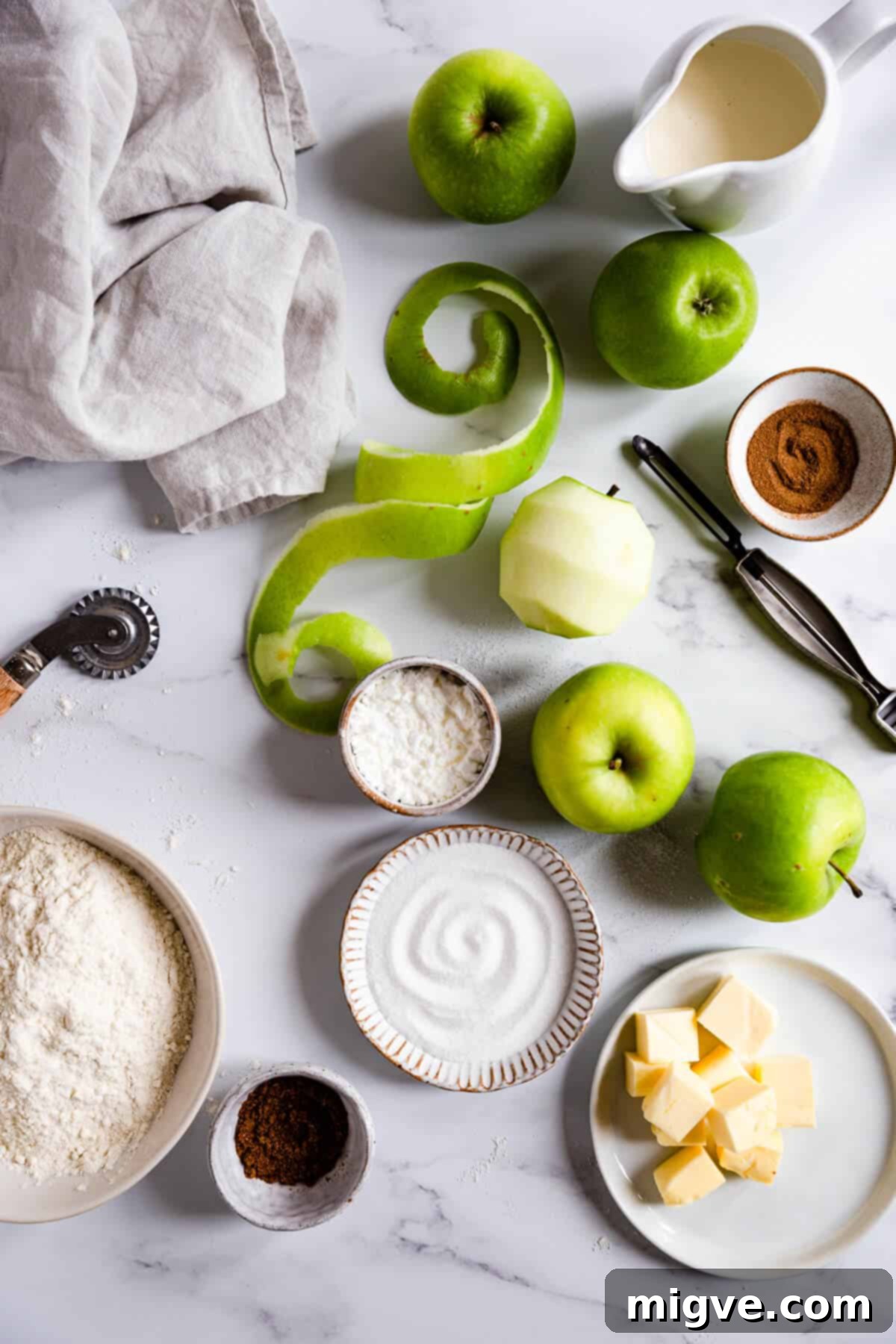 An overhead shot showcasing various raw ingredients for apple pie, including whole apples, flour, butter, and spices, neatly arranged on a rustic wooden surface.