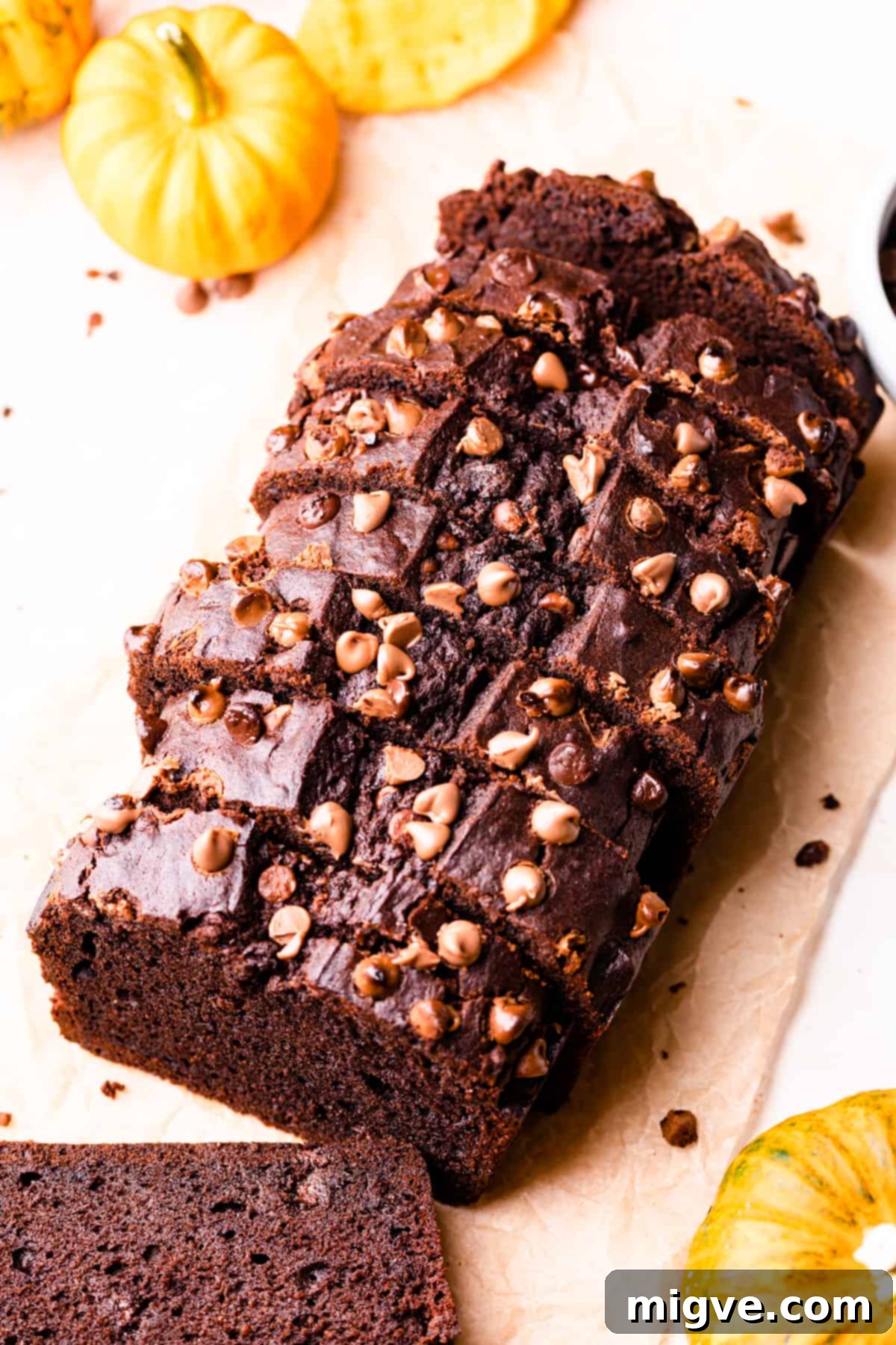 Slices of moist chocolate pumpkin loaf with visible chocolate chips, artfully arranged on a wooden board.