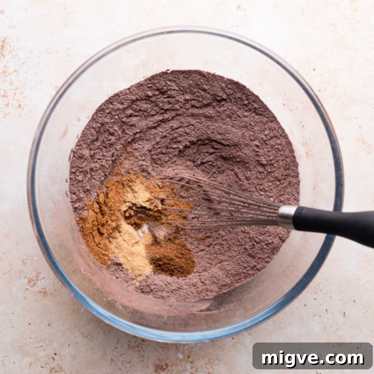 A large bowl containing a perfectly mixed blend of flour, cocoa powder, and various warm spices, ready for the wet ingredients.