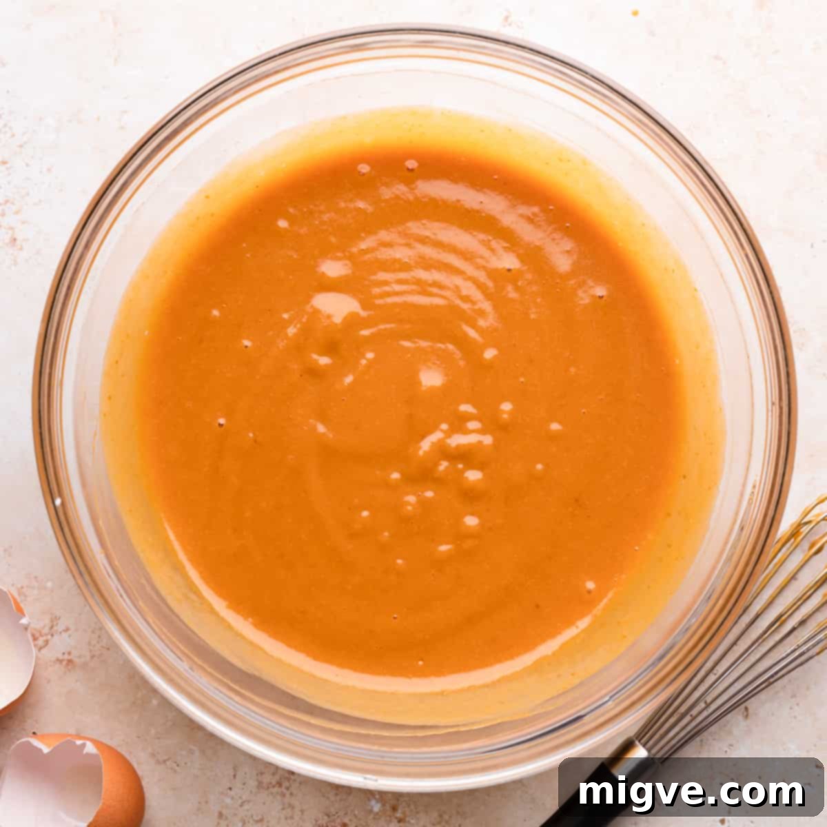 A separate bowl holding the whisked wet ingredients for pumpkin bread with chocolate, including pumpkin puree, sugar, oil, buttermilk, eggs, and vanilla extract.