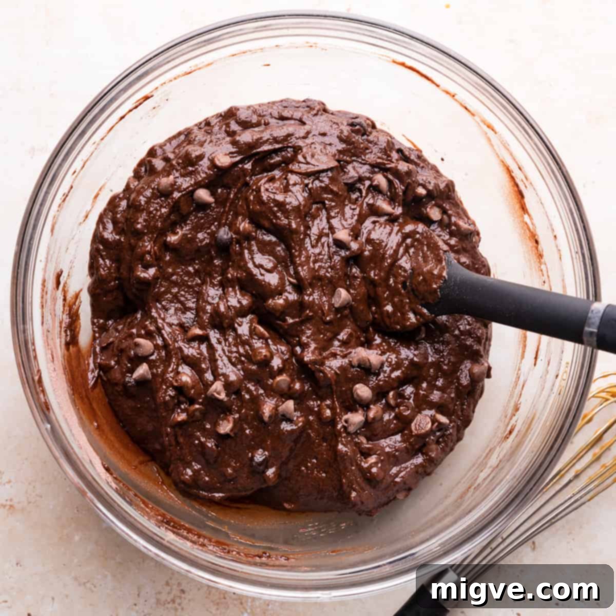 A large mixing bowl containing the chocolate pumpkin bread batter, with a generous amount of chocolate chips gently folded in.