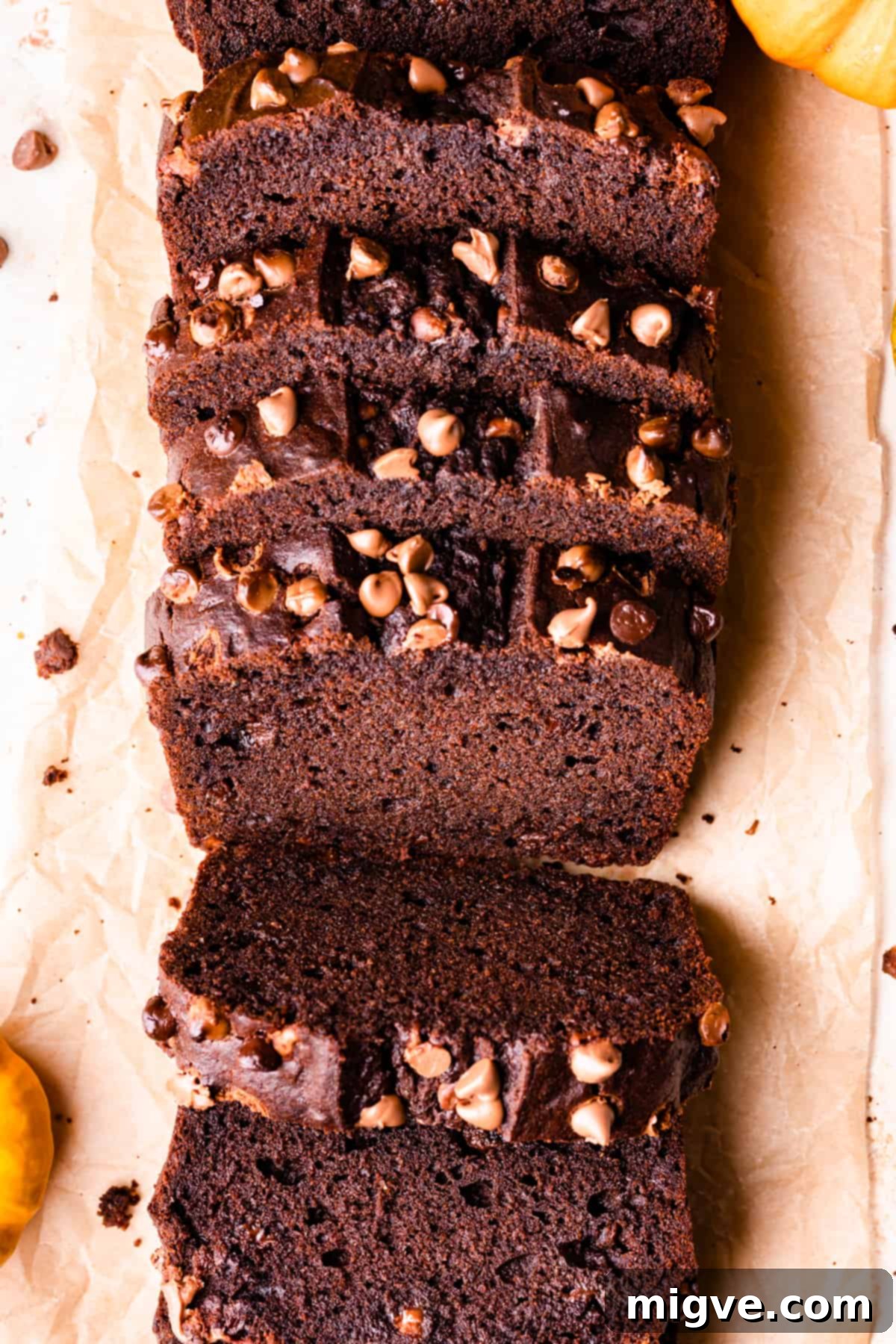 Perfectly cut slices of chocolate pumpkin bread, showing off its moist, spiced interior and generous chocolate chips, arranged on brown baking paper.