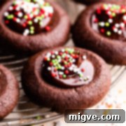 Side close up at a single chocolate thumbprint cookie on a round wire rack