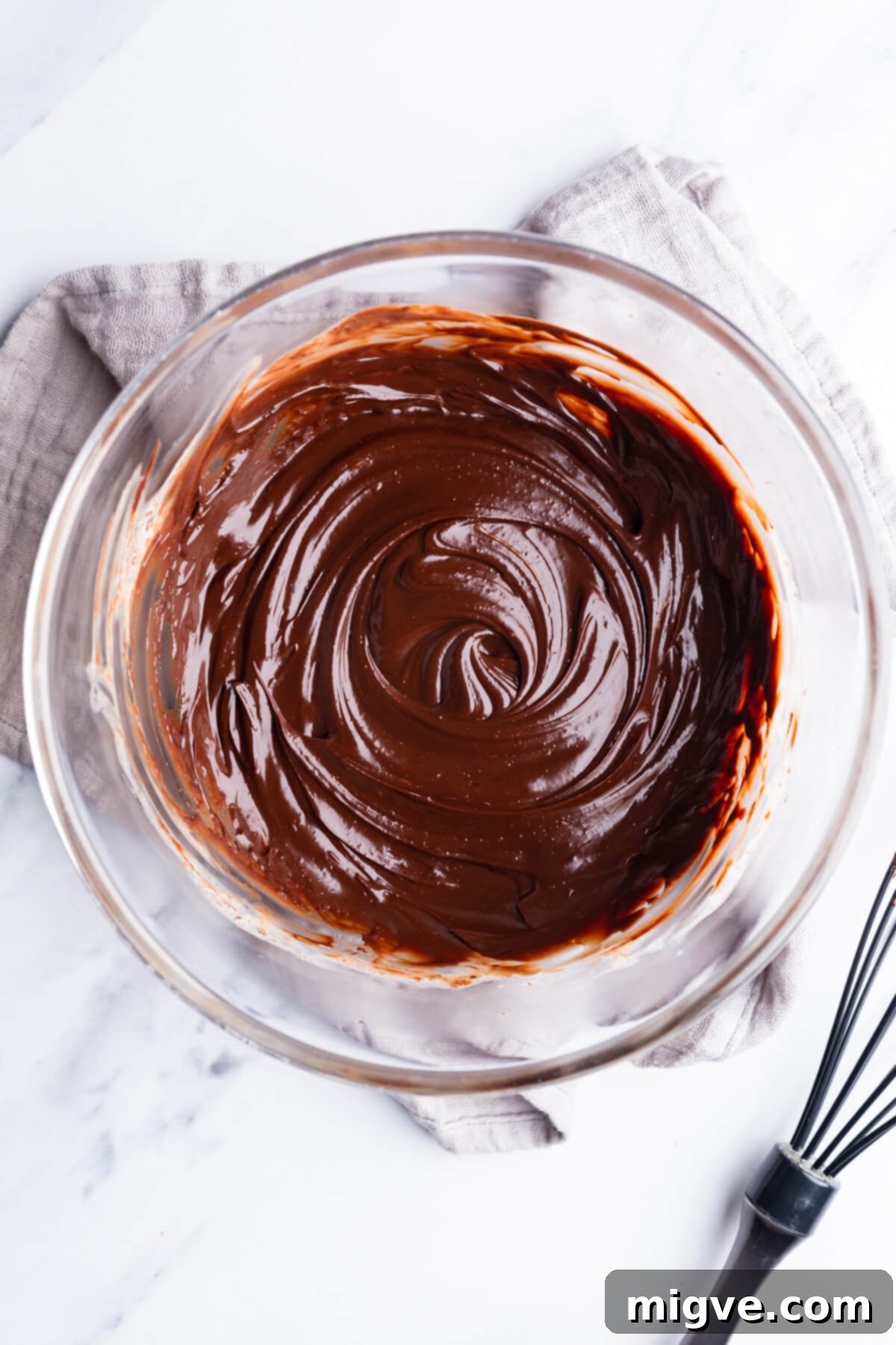 Overhead close-up view of a large bowl filled with perfectly smooth, glossy chocolate ganache, ready to be used as a filling.