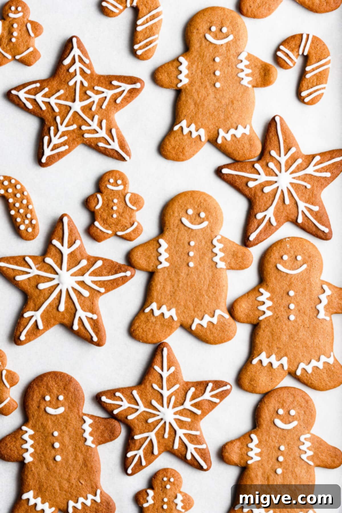 Pillowy Soft Gingerbread Cookies 11 Overhead shot of an assortment of festive gingerbread cookies arranged artfully on a white surface, each decorated with unique icing patterns.