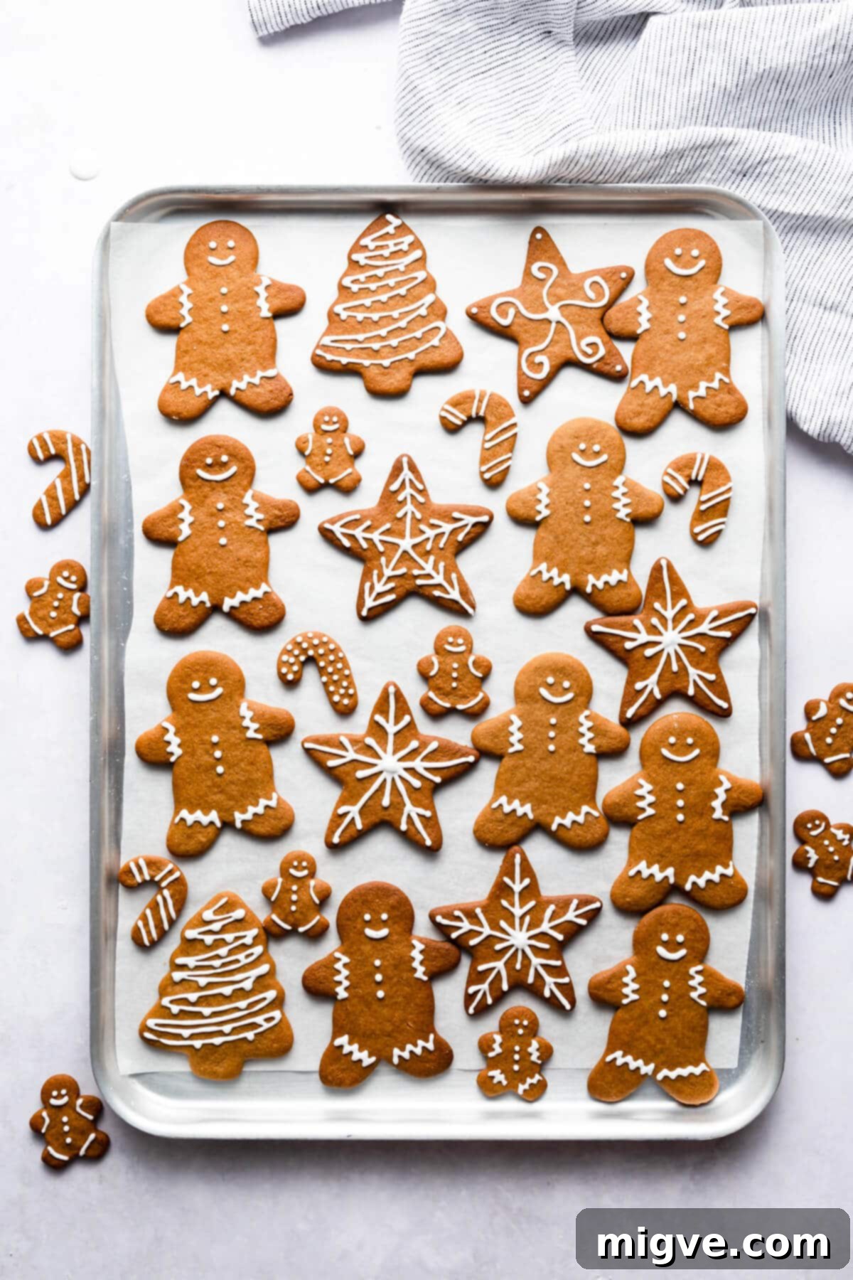 Pillowy Soft Gingerbread Cookies 12 Top-down view of a baking sheet completely filled with an assortment of baked and decorated soft gingerbread cookies, showcasing various festive shapes and icing designs.