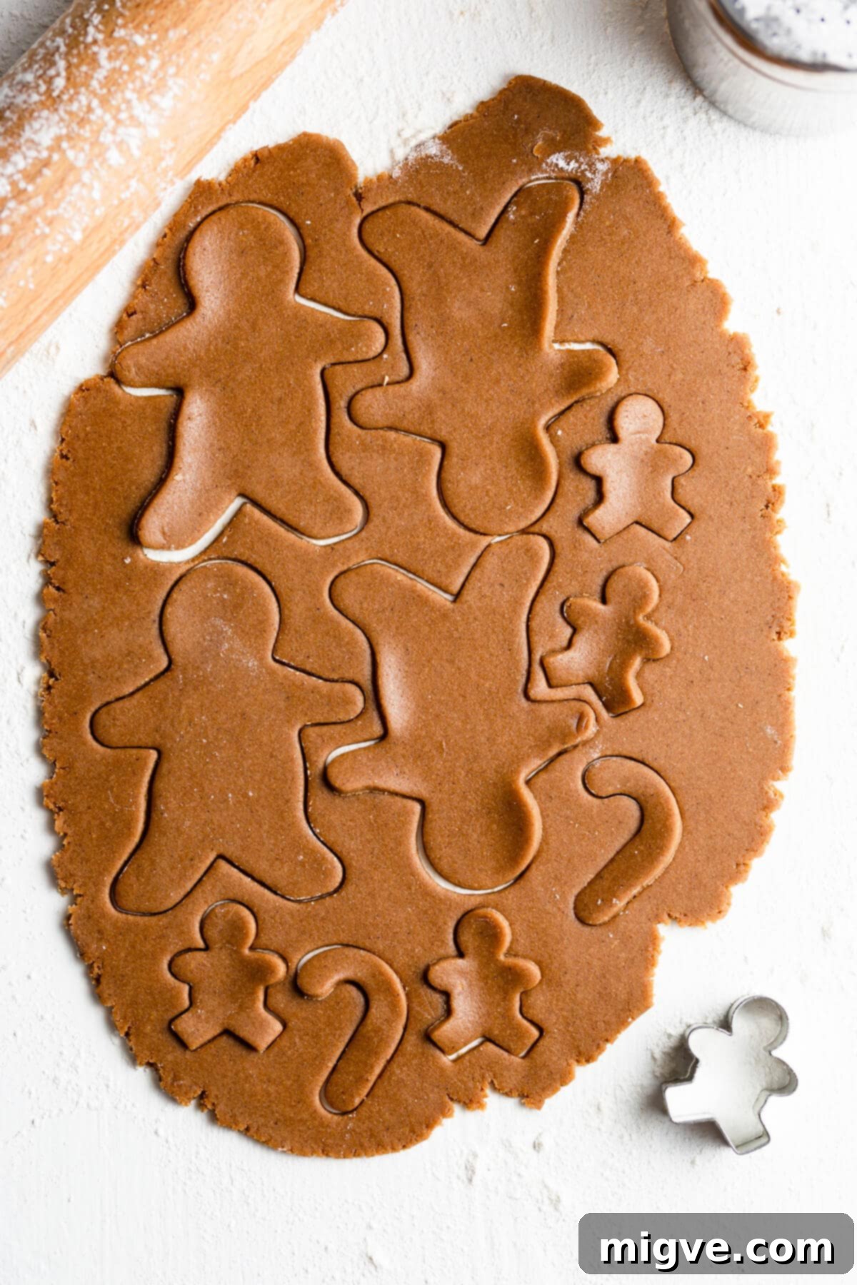 Pillowy Soft Gingerbread Cookies 7 Top-down shot of rolled gingerbread cookie dough with various festive shapes like stars and gingerbread men already cut out, ready for baking.