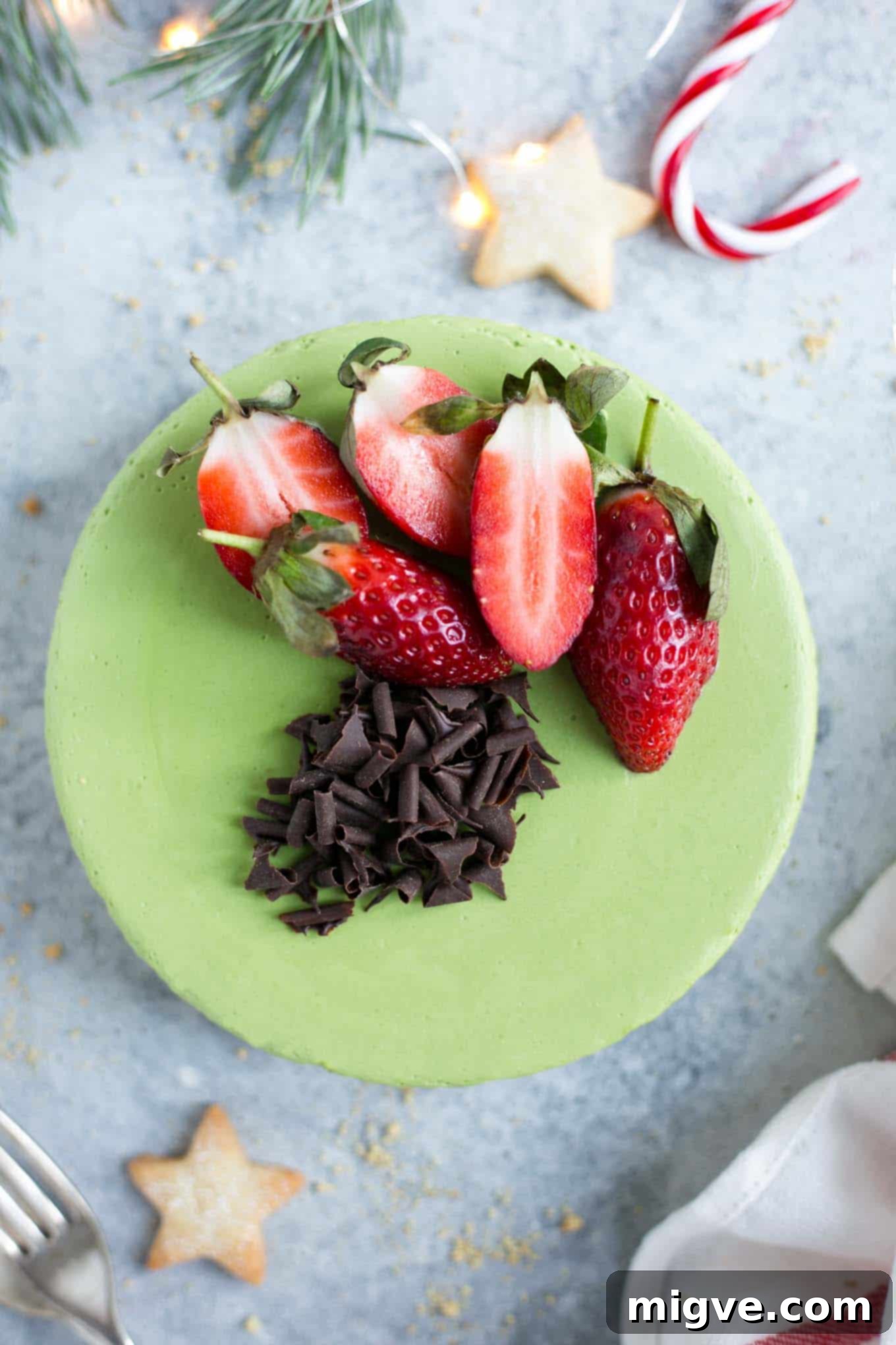 An overhead shot of the velvety vegan matcha ginger cheesecake, topped with fresh raspberries and a dusting of matcha powder, highlighting its rich texture.