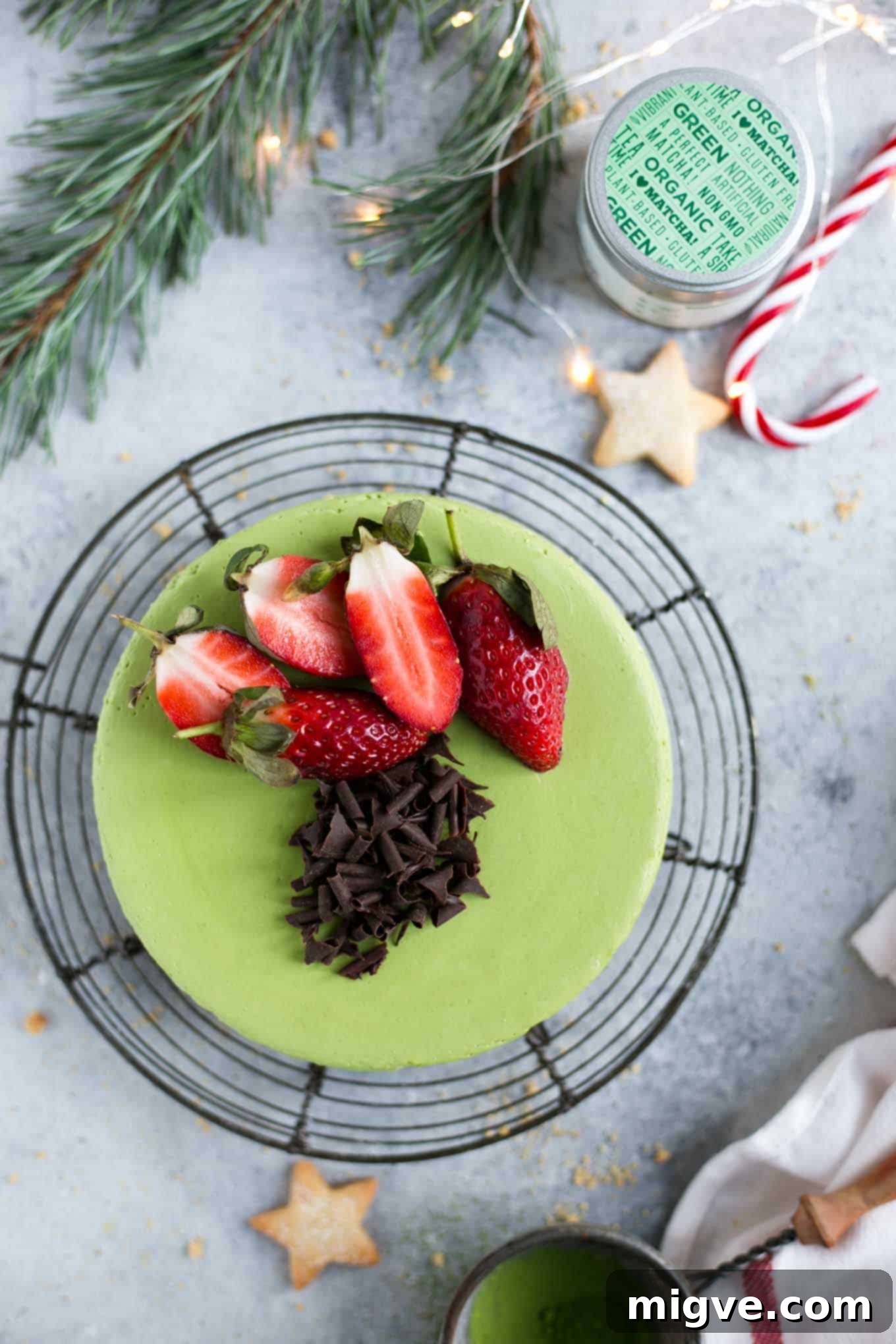 A slice of creamy vegan matcha ginger cheesecake on a plate, garnished with fresh mint and berries, showcasing its appealing texture and rich green color.