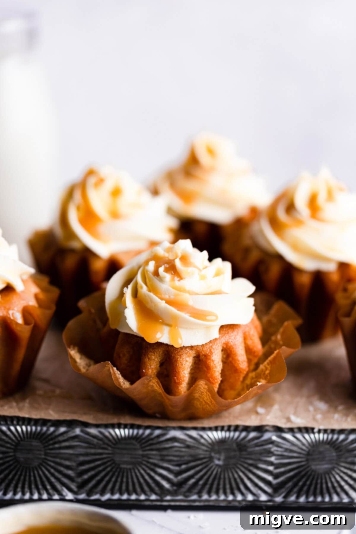 Close-up side view of a beautifully frosted vegan salted caramel cupcake, highlighting the texture of the buttercream and the shiny caramel.