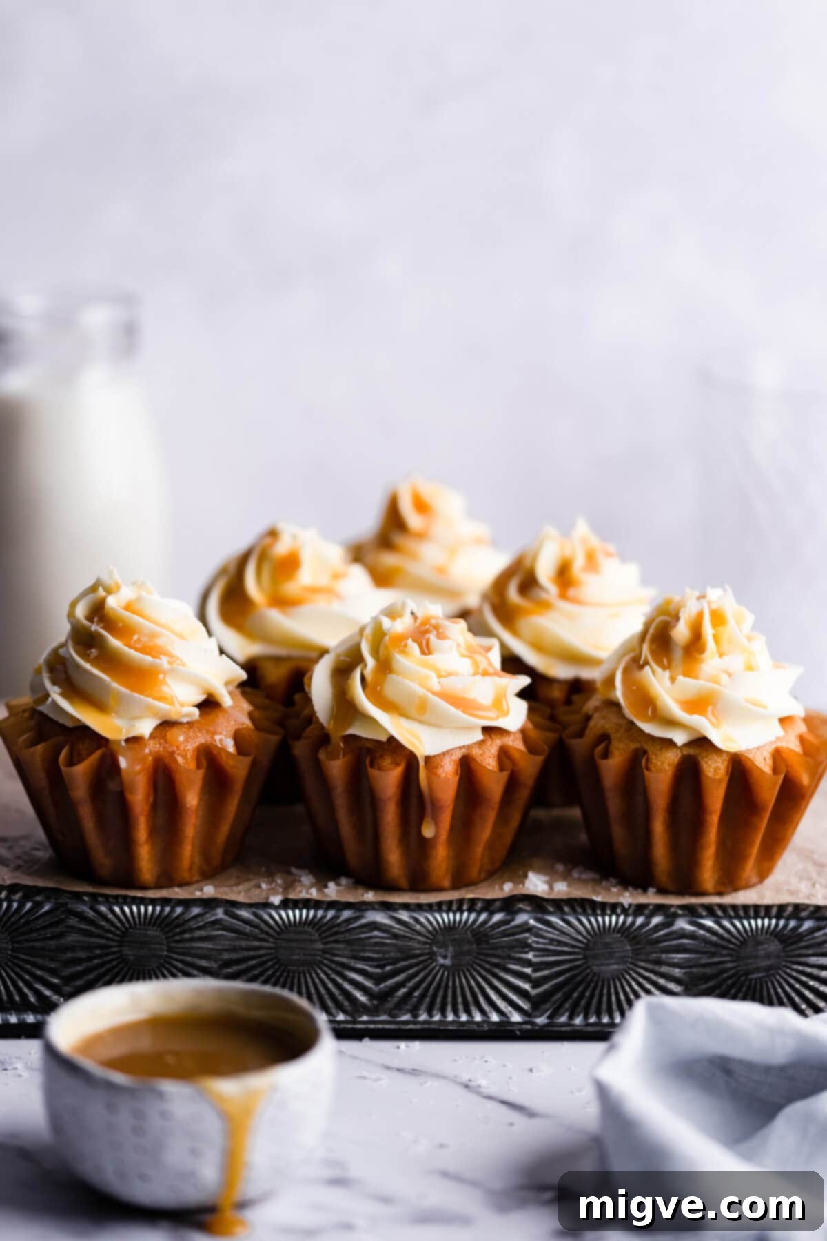 A beautiful array of vegan salted caramel cupcakes, artfully arranged on a metal baking tray, ready to be enjoyed.