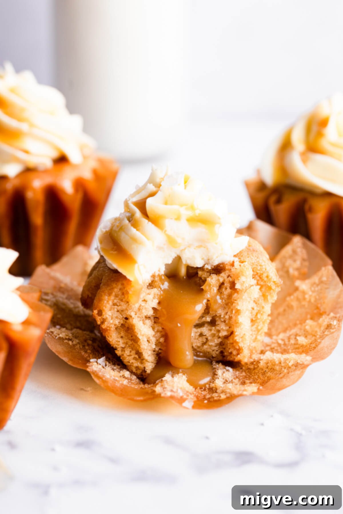 A vegan salted caramel cupcake with a bite taken out, revealing the rich, gooey caramel center, highlighting its deliciousness.