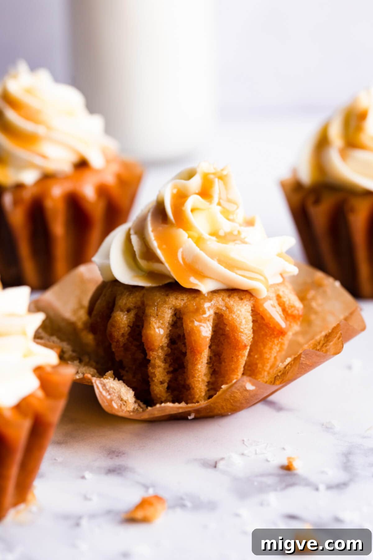 A super close-up side view of a vegan salted caramel cupcake, highlighting the rich buttercream swirls and delicate caramel drizzle.