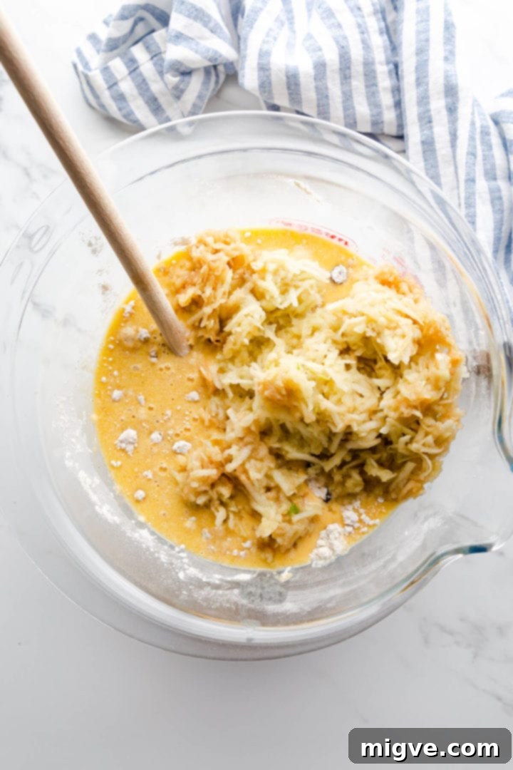 top view of mixing bowl with dry and wet ingredients and grated apples